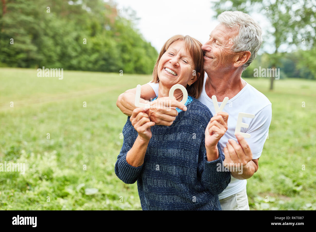 Senioren als glückliches Paar im Park buchstabiere das Wort Liebe Stockfoto