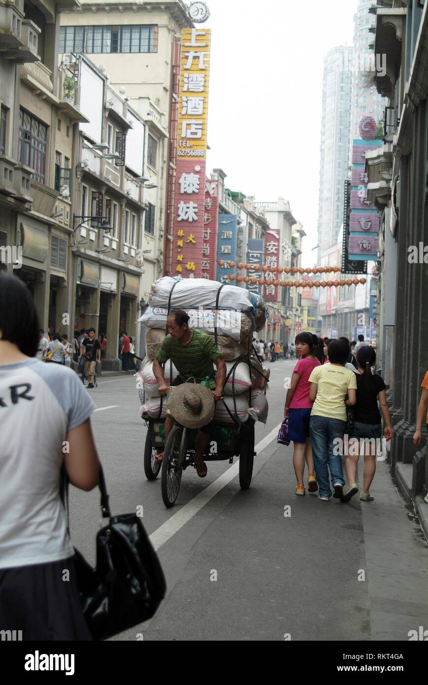 Eine Ladung Taxi verhandelt die Straße zwischen Käufer auf einer belebten Straße in Guangzhou. Einen Hafen und Stadt von 6 Millionen auf den Pearl River in der Nähe von Hong Kong, Gu Stockfoto