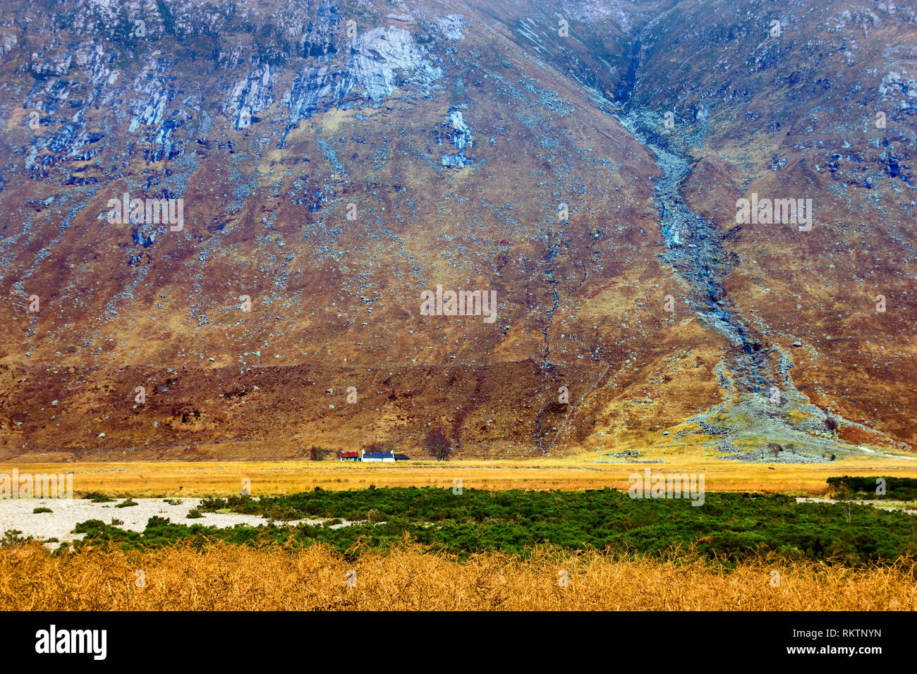 Ein Blick auf eine abgelegene Farm von einem hoch aufragenden Berg in den schottischen Highlands in den Schatten gestellt. Stockfoto