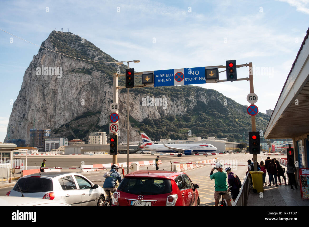 Ein Flugzeug des British Airways Airbus A320 startet auf der Straße, während der Verkehr und Fußgänger auf der berühmten Pistenüberquerung am Flughafen Gibraltar warten Stockfoto