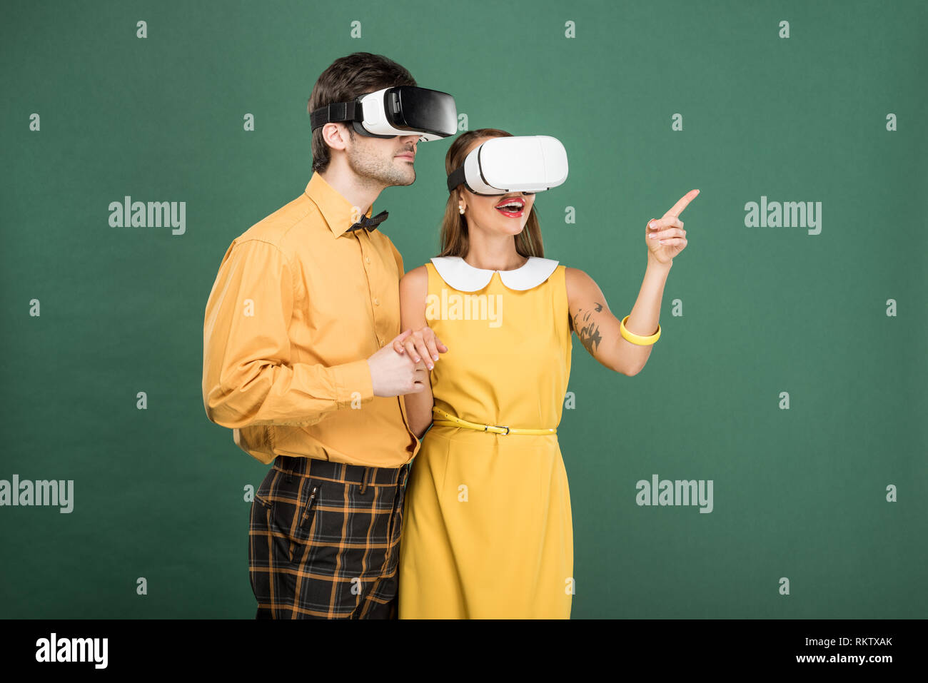 Aufgeregt Paar in Vintage Kleidung und Virtual reality Headset isoliert auf Grün Stockfoto