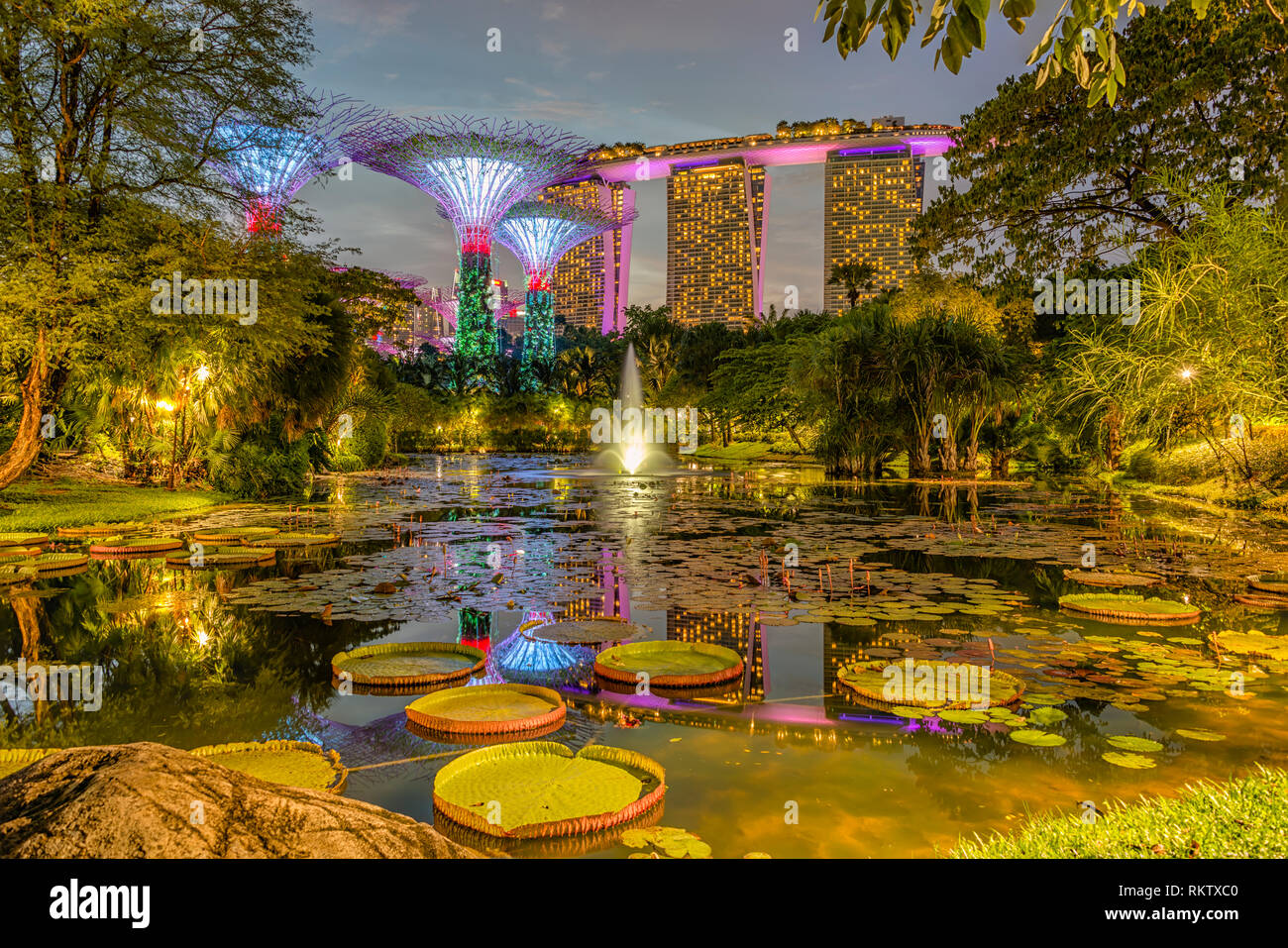 Beleuchtete Gärten an der Bucht bei Nacht mit dem Marina Bay Sands Hotel im Hintergrund, Singapur Stockfoto