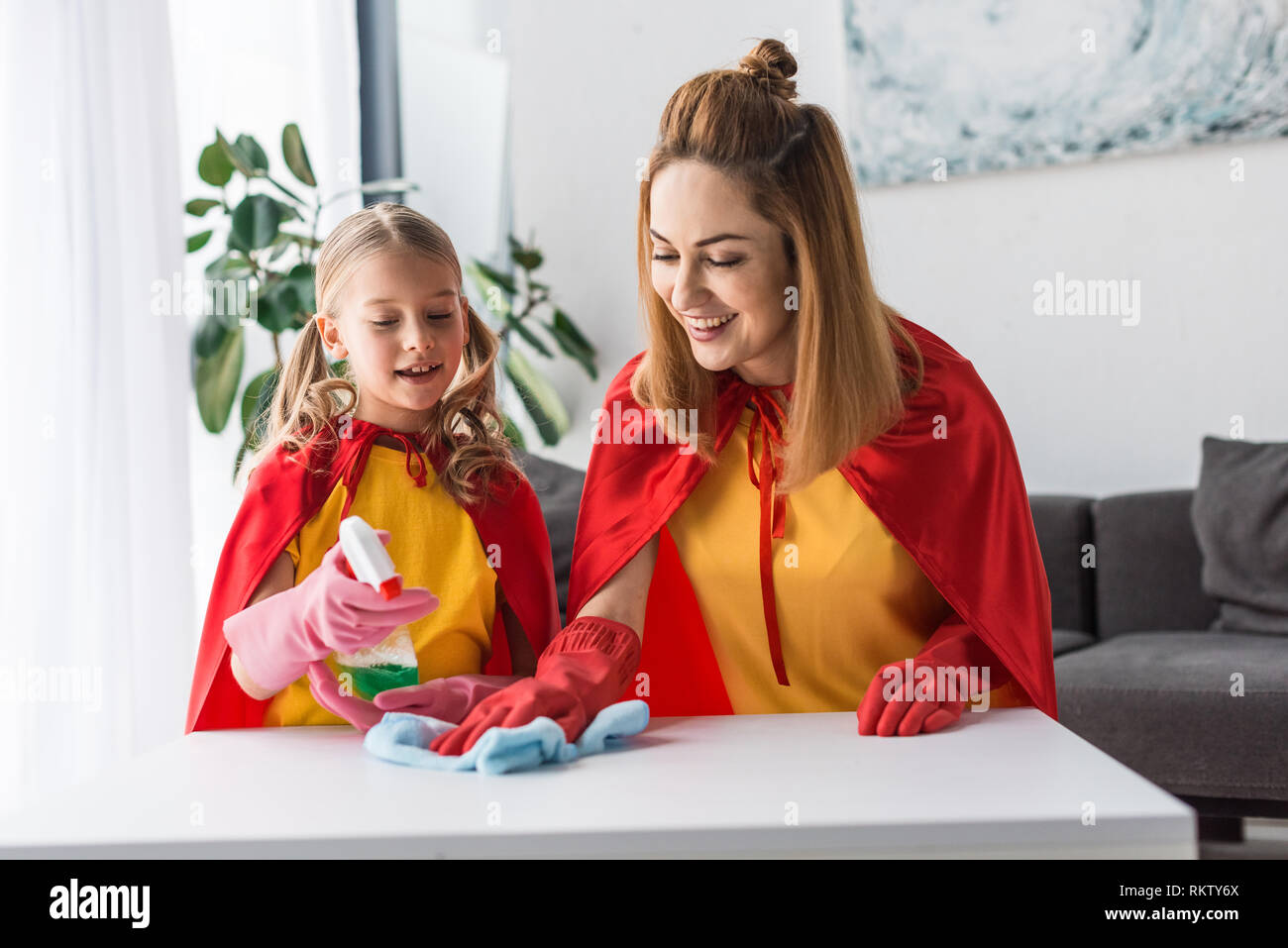Mutter und Kind in Red Caps und Gummihandschuhe abstauben zu Hause Stockfoto