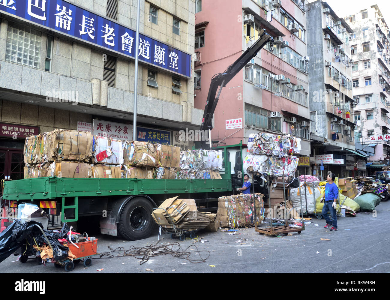 Blöcke von Altpapier auf einen Kran-LKW geladen wird auf der Straße von Sham Shui Po, Hongkong. Stockfoto