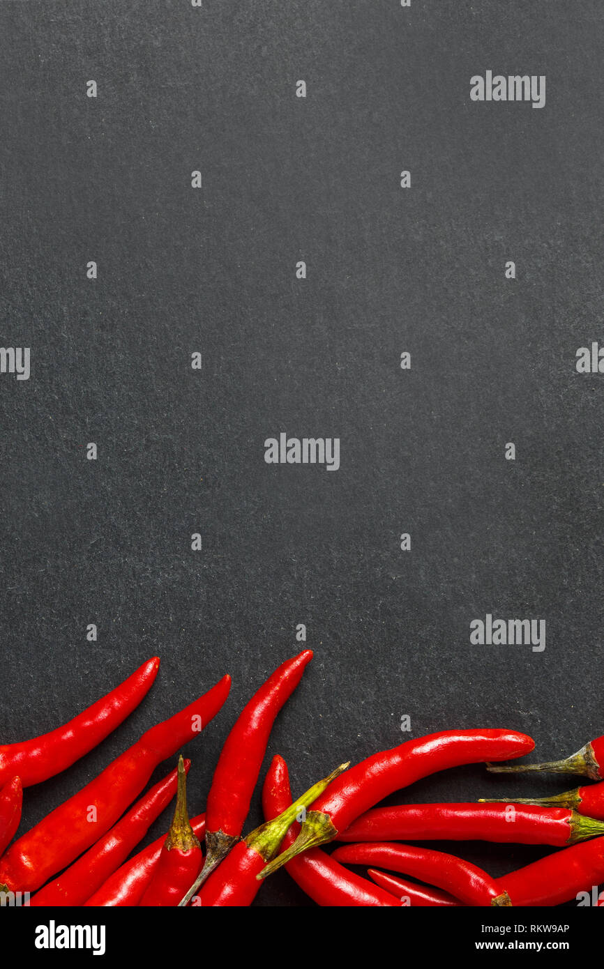 Frische reife red hot chili peppers auf einen schwarzen Stein Hintergrund Stockfoto