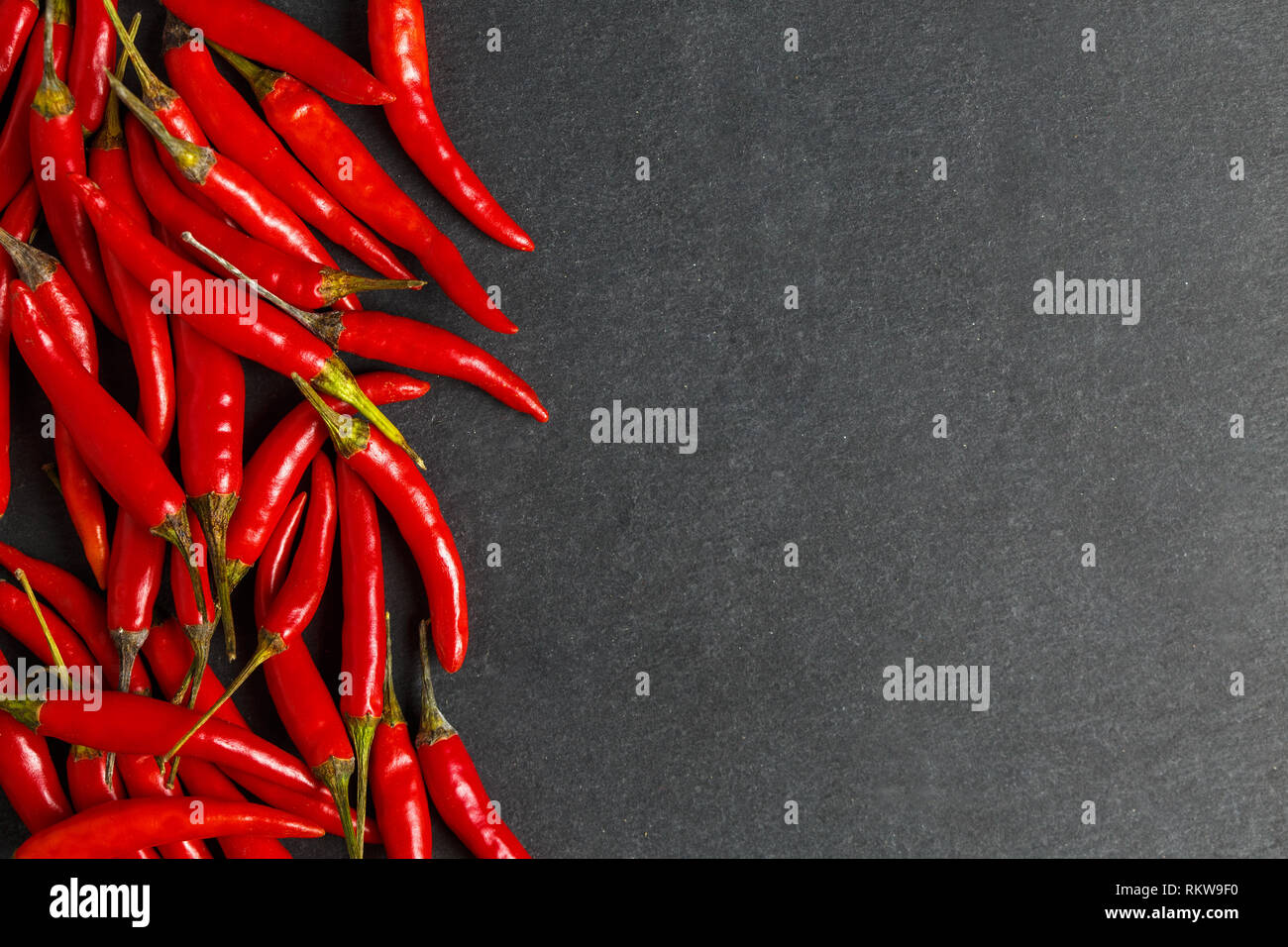Frische reife red hot chili peppers auf einen schwarzen Stein Hintergrund Stockfoto
