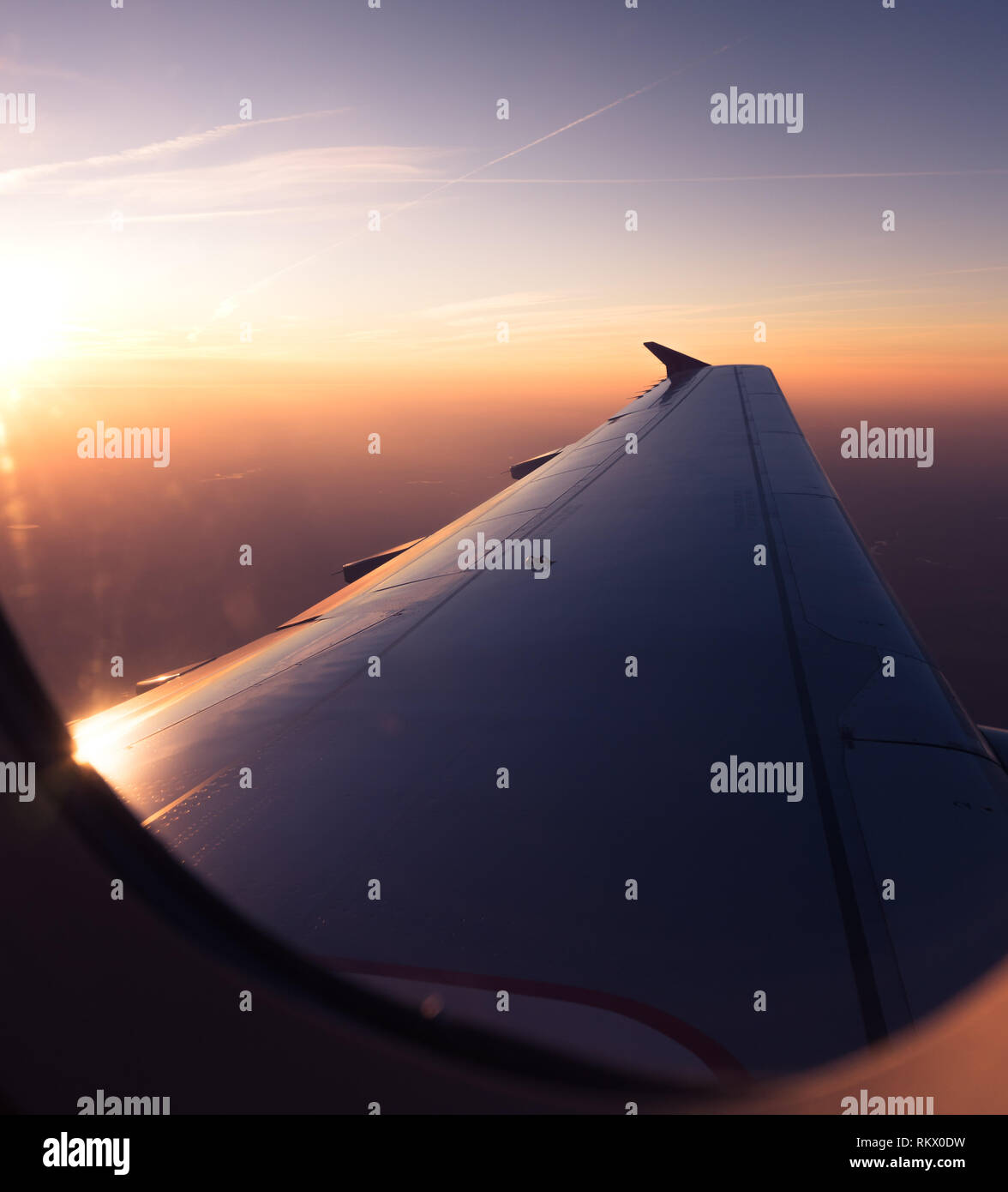Passagier POV Blick durch die Flugzeugfenster, Sonnenaufgang über den Wolken Antenne Stockfoto