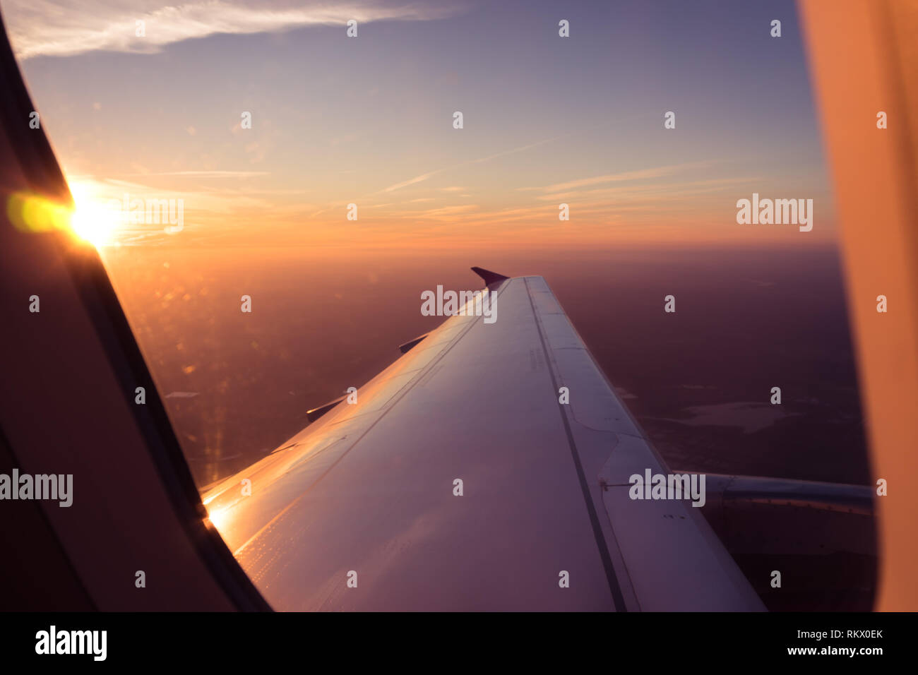 Passagier POV Blick durch die Flugzeugfenster, Sonnenaufgang über den Wolken Antenne Stockfoto