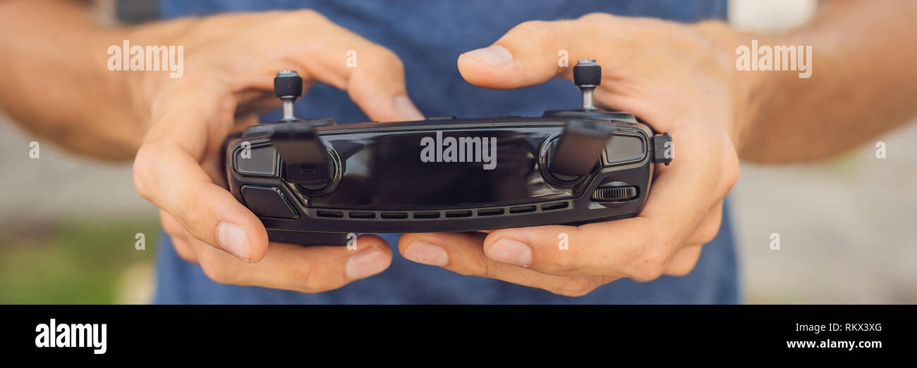 Mann hält Remote Controller mit seinen Händen und steuert die Drohne. Neue Technologien und Innovationen Konzept BANNER lange Format Stockfoto