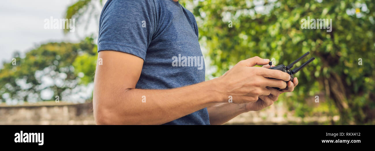 Mann hält Remote Controller mit seinen Händen und steuert die Drohne. Neue Technologien und Innovationen Konzept BANNER lange Format Stockfoto