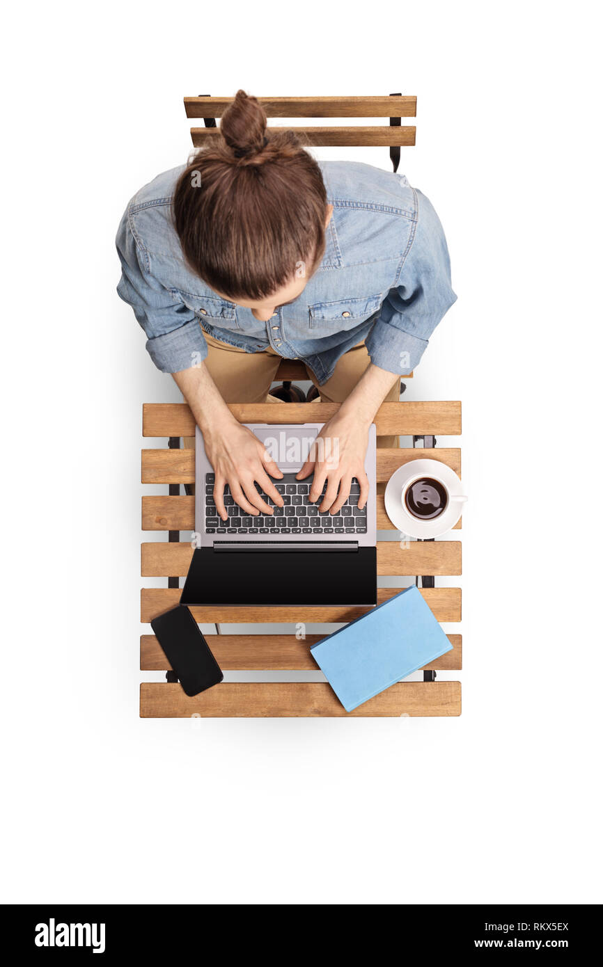 Blick von oben auf einen jungen Mann, der an einem Notebook arbeitet und sitzen auf einem hölzernen Couchtisch auf weißem Hintergrund Stockfoto