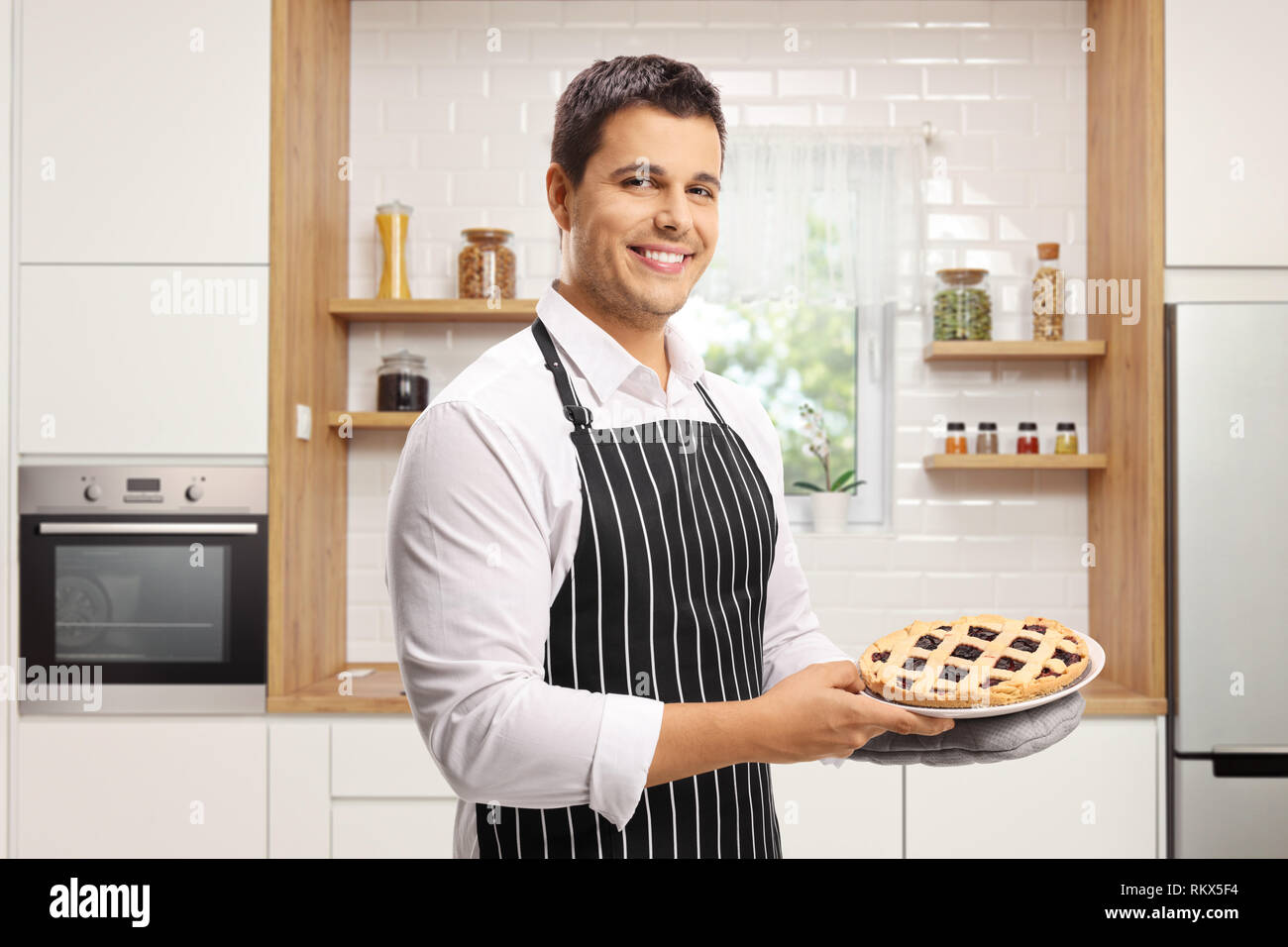 Junger Mann mit einer Torte in einer modernen Küche Stockfoto