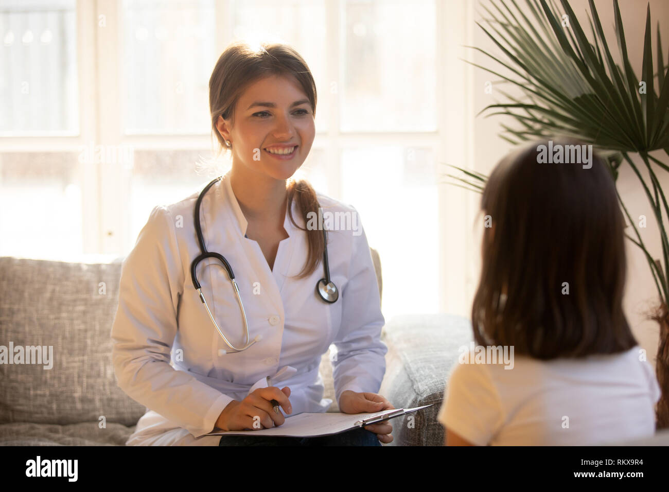 Freundliche Hündin Arzt Kinderarzt holding Zwischenablage Anhören kid Patient Stockfoto