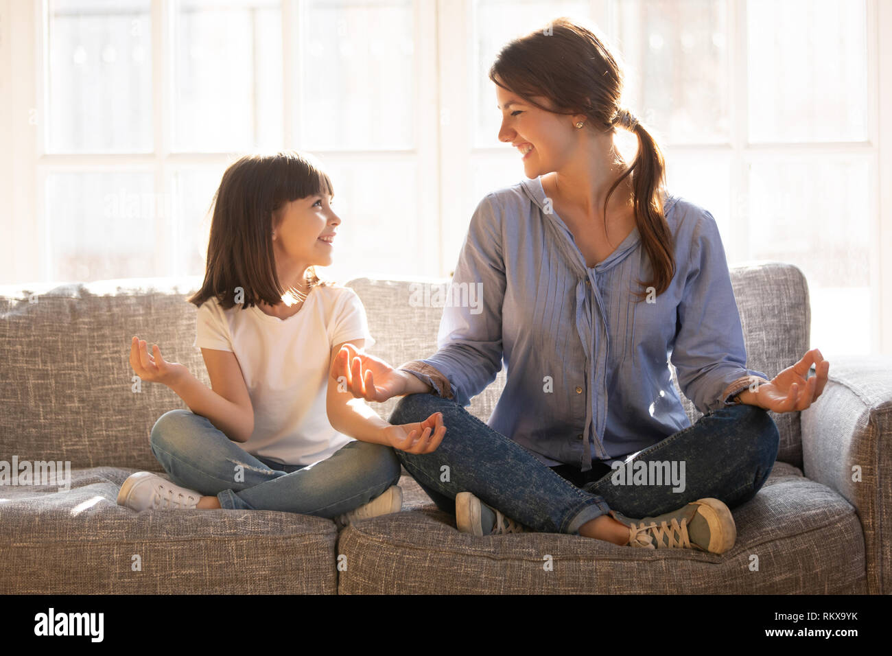 Eingedenk mama Yoga glückliches Kind Tochter sitzen auf der Couch Stockfoto
