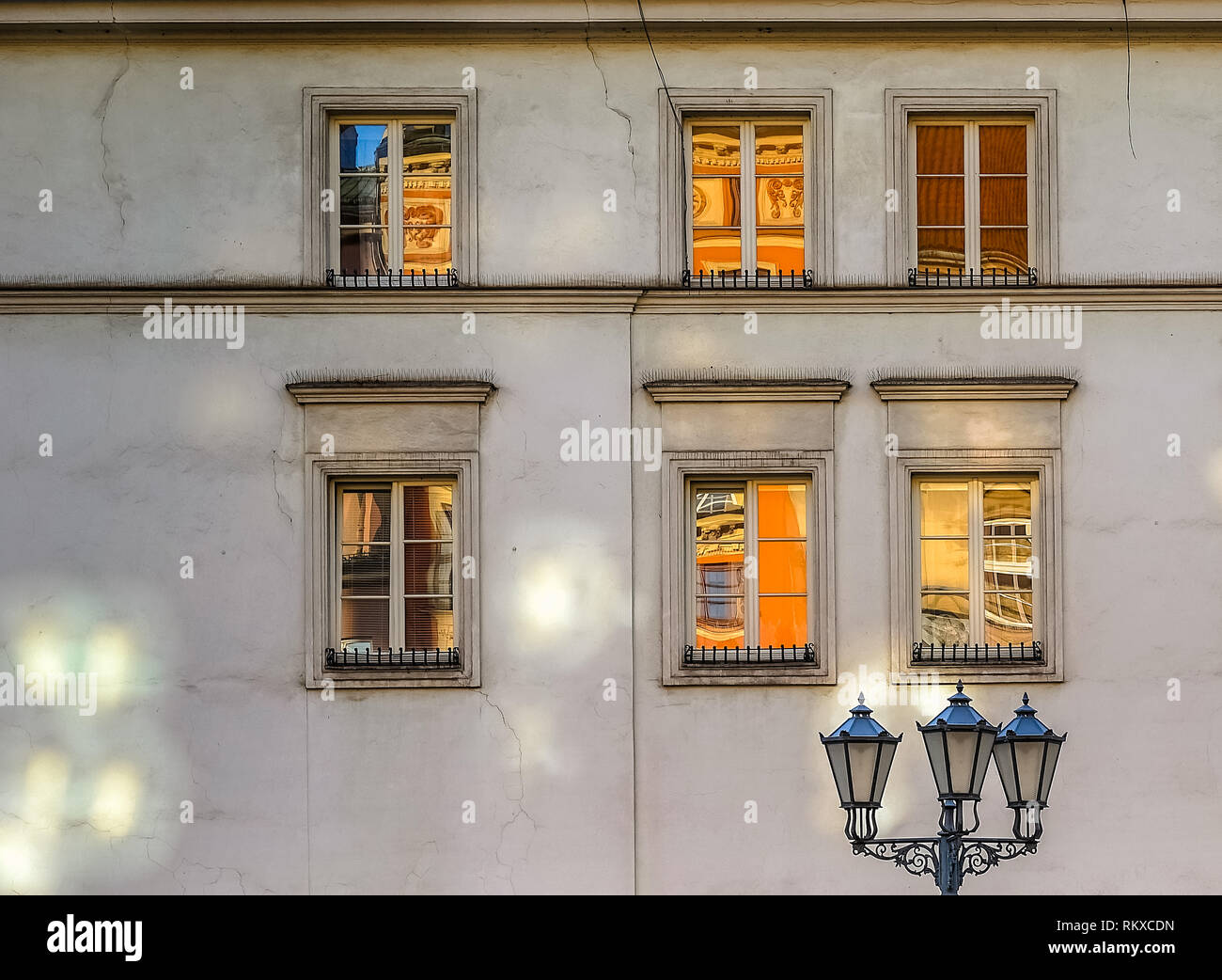 Street Light und sechs alte Fenster an der Wand mit Reflexionen der Altstadt in Krakau bei Sonnenaufgang Stockfoto
