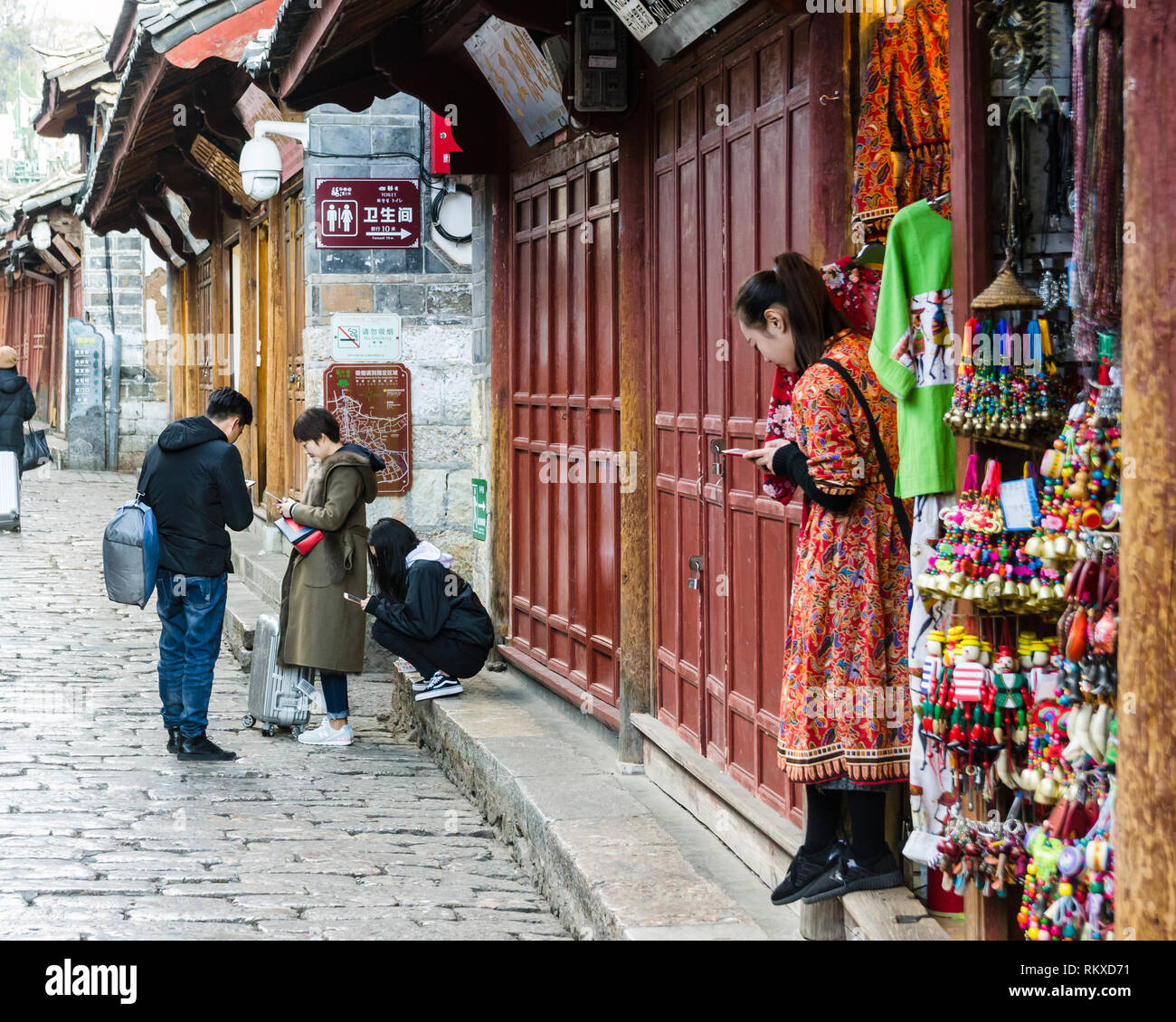 Touristen und Einheimische in Lijiang Altstadt auf ihren Mobiltelefonen, China Stockfoto