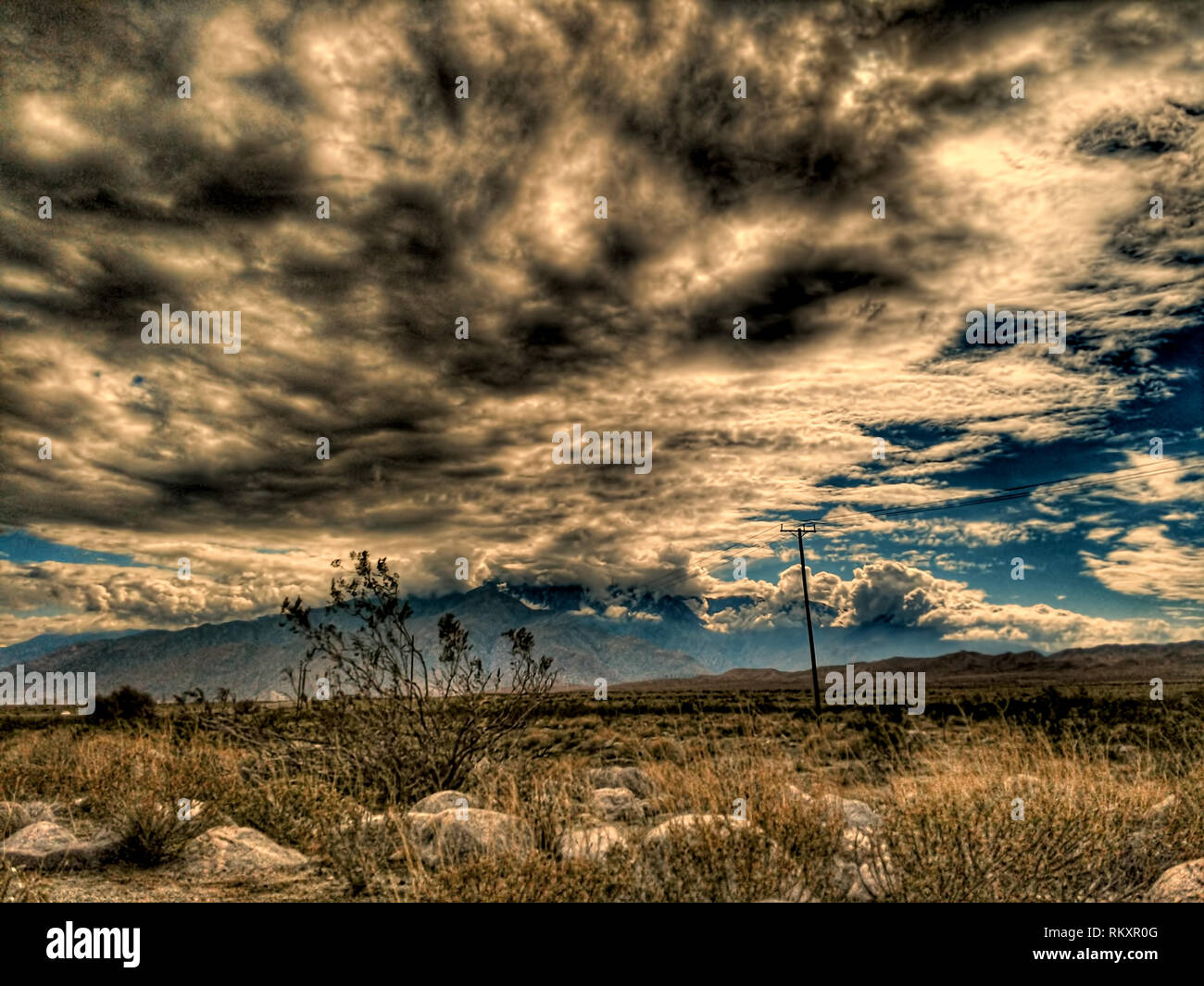 Stürmischen regen Wolken sammeln über den sandigen Pinsel in der kalifornischen Mojave-Wüste in der Nähe von Bergen. Stockfoto