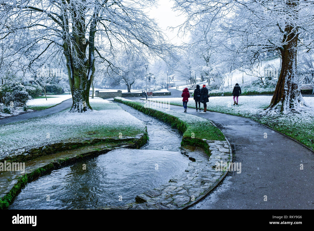 Die Menschen genießen einen Spaziergang im Schnee in Trenance Gärten in Newquay in Cornwall. Stockfoto