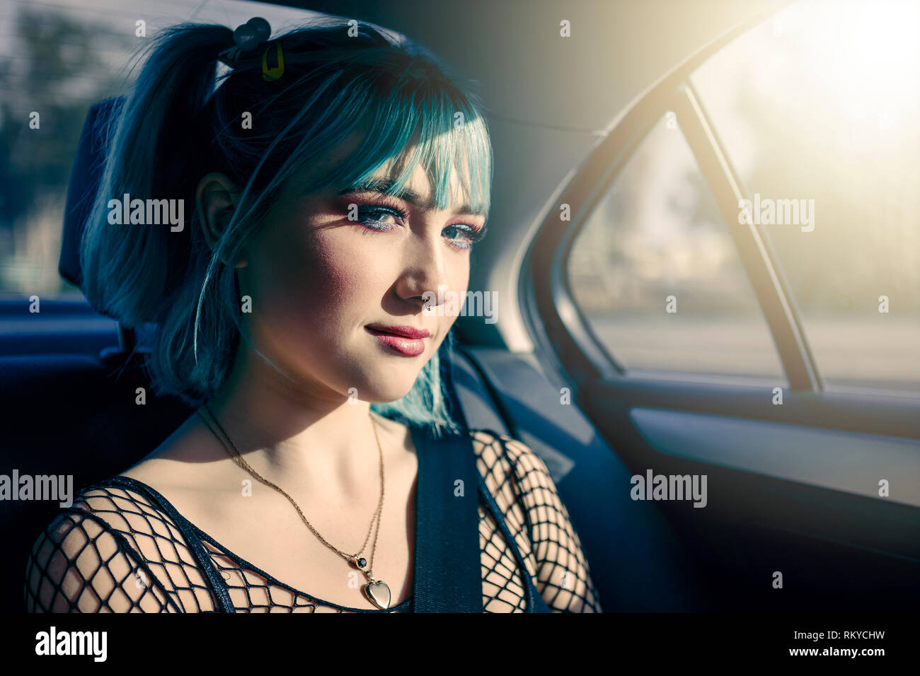 Portrait von jugendlich Mädchen mit blauen Haaren und durchbohrt Nase auf dem Rücksitz eines Autos während auf einem Roadtrip. Stockfoto
