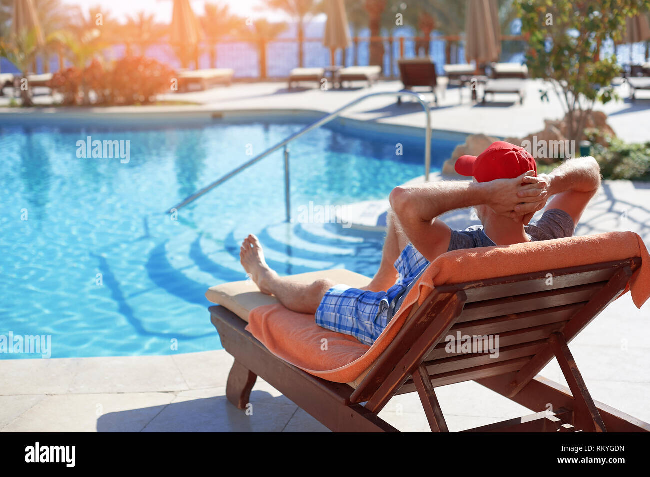 Positiver Mann in Red Hat ruht in der Nähe des Pool Hotel in Ägypten. Konzept schönen Lebensstil Stockfoto Positiver Mann in Red Hat ruht in der Nähe des Pool Hotel in Ägypten. Konzept schönen Lebensstil Stockfoto