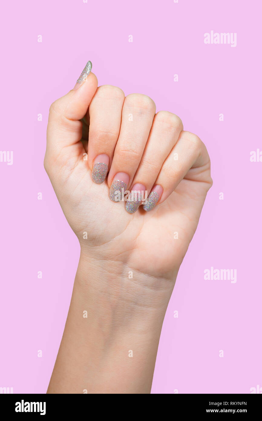 Detailansicht schöne weibliche Hände mit alten Silber funkelnde Maniküre auf rosa Hintergrund isoliert. Frau braucht Korrektur. Vertikale Farbe Photogra Stockfoto