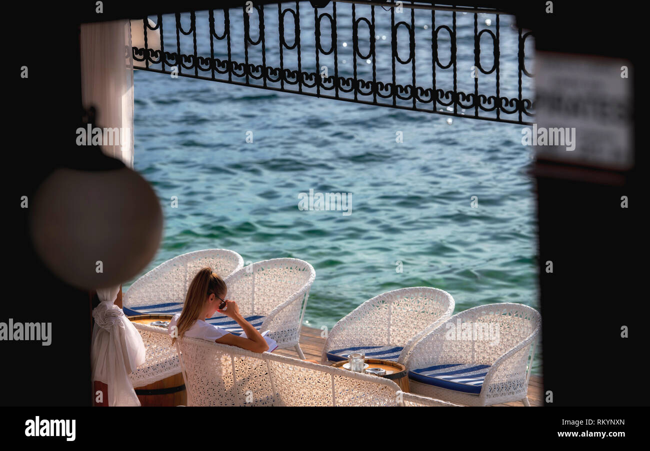 Mädchen das Lesen eines Buches in Seaside Cafe am tiefblauen Mittelmeer in Montenegro. Stockfoto