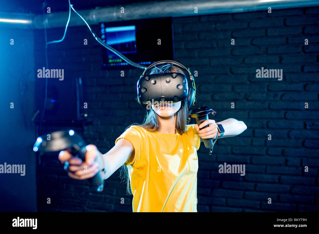 Junge Frau spielen Spiel mit Virtual reality Headsets und Gamepads im dunklen Raum der spielenden Club Stockfoto