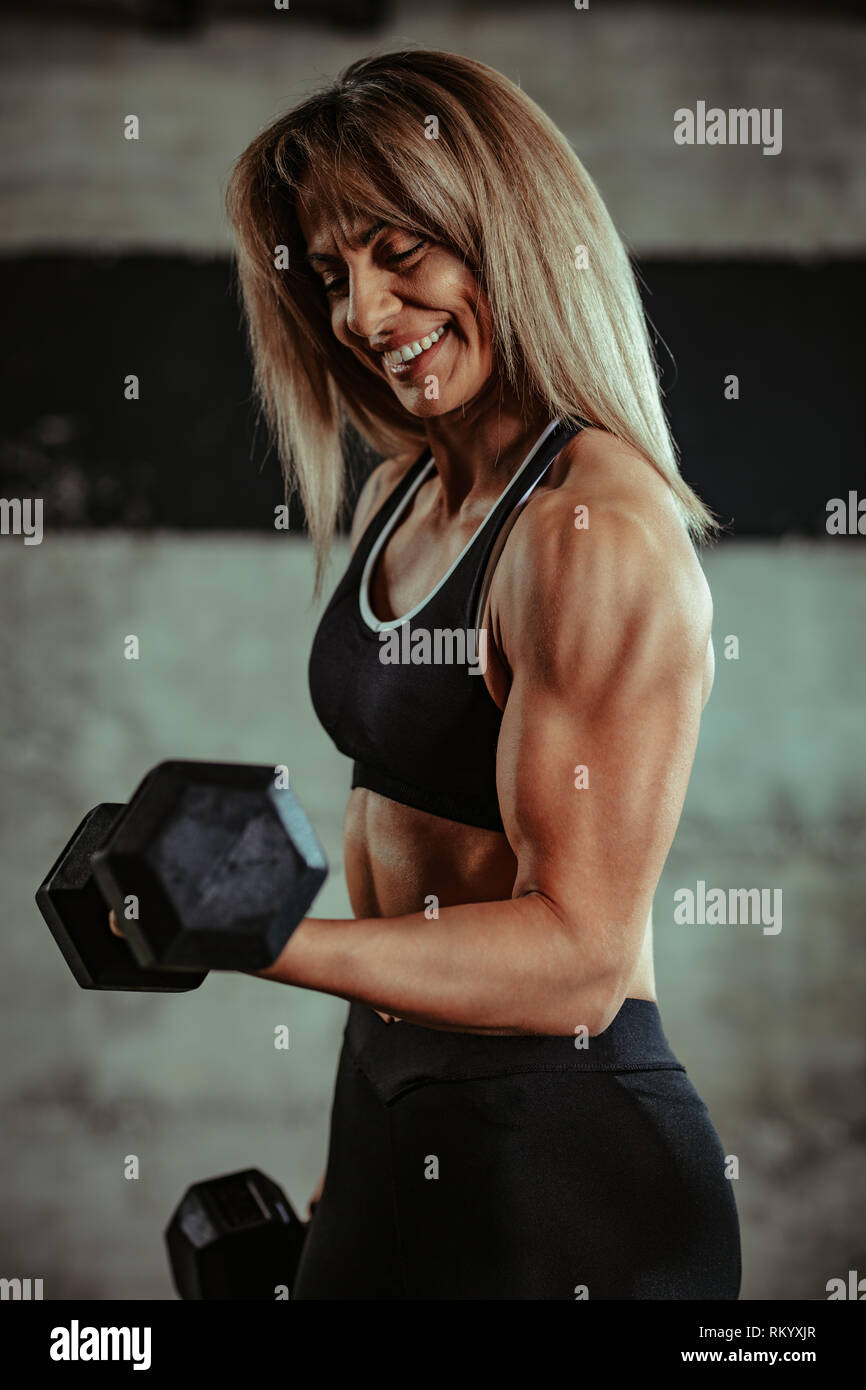 Muskulöse schöne Frau ist, trainieren Sie im Fitnessraum mit Hanteln. Stockfoto
