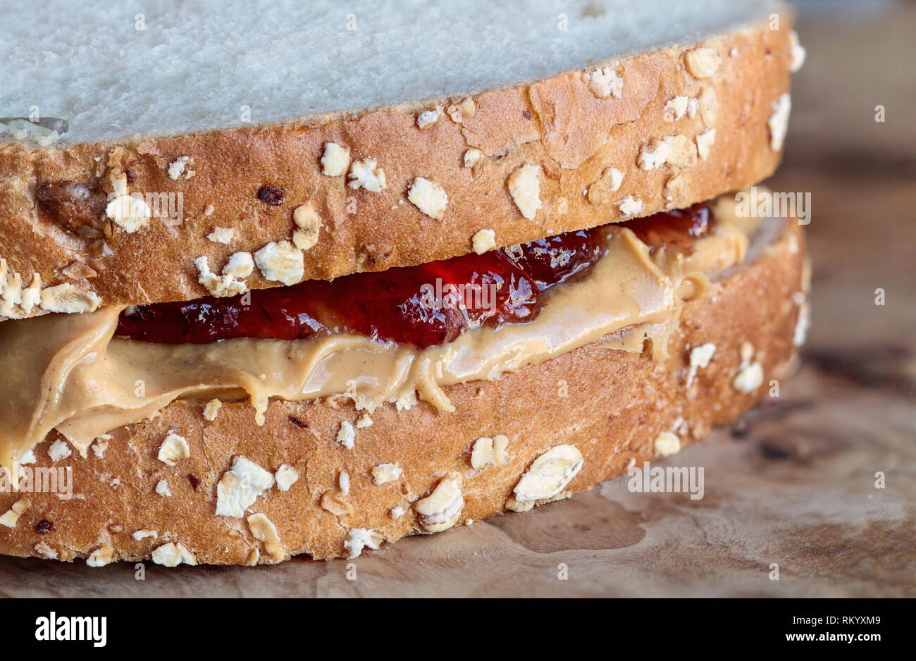 Hausgemachte Peanut Butter und Marmelade Sandwich auf Hafer Brot, über einen rustikalen Holzmöbeln Hintergrund für das Mittagessen bereit. Stockfoto