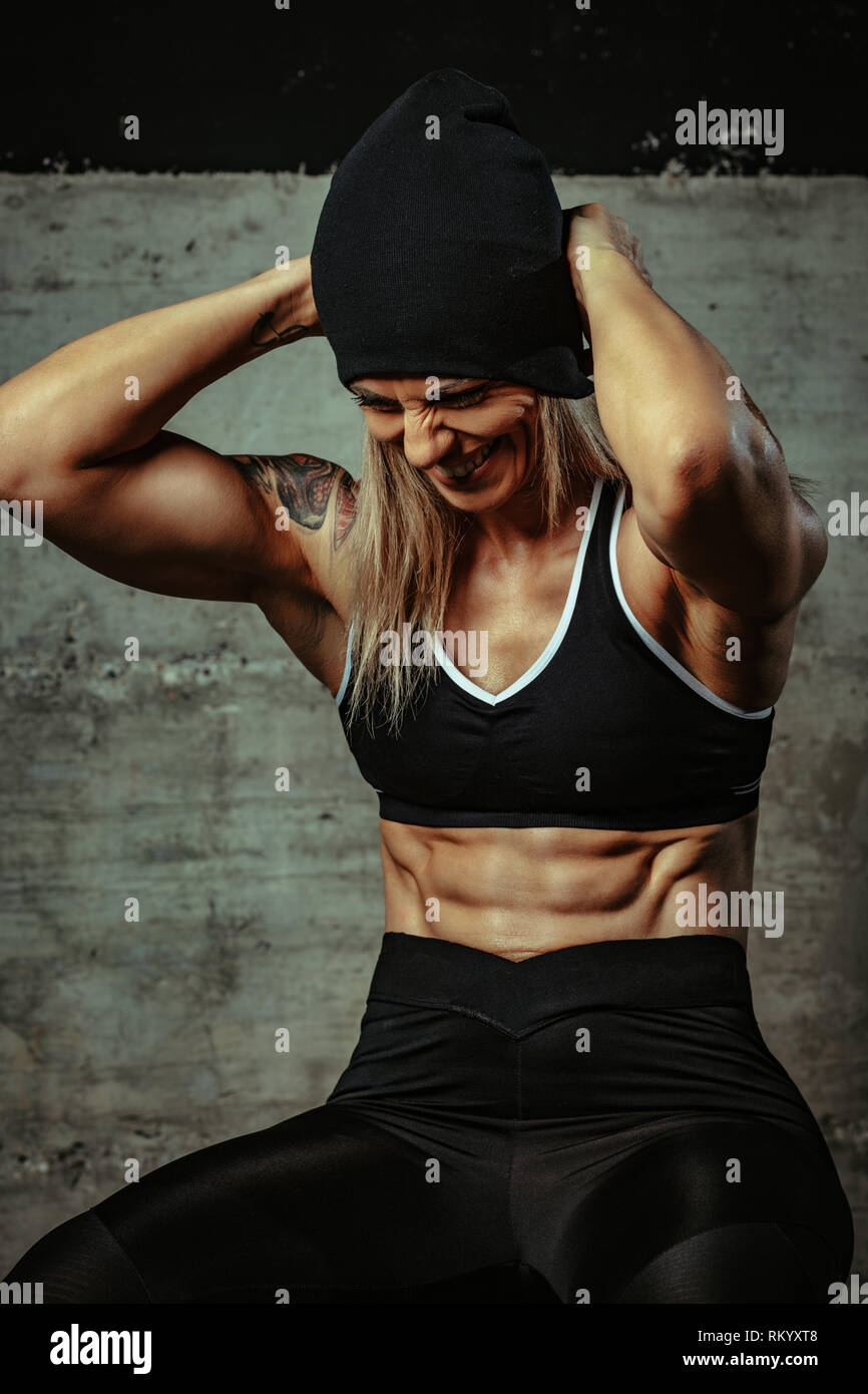 Junge muskulöse schöne Frau ruht sich nach dem Training im Fitnessraum. Stockfoto