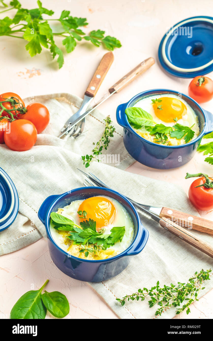 Eier kokot Cocotte französisches Frühstück. Gebackene Eier in blau Keramik Backformen. Portioniert Auflauf aus Gemüse und Eier im italienischen Stil. Stockfoto