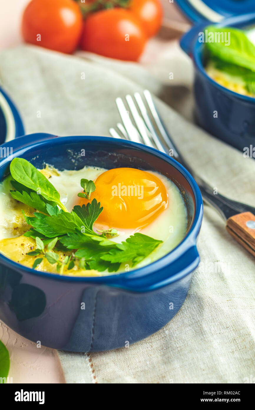 Eier kokot Cocotte französisches Frühstück. Gebackene Eier in blau Keramik Backformen. Portioniert Auflauf aus Gemüse und Eier im italienischen Stil. Stockfoto
