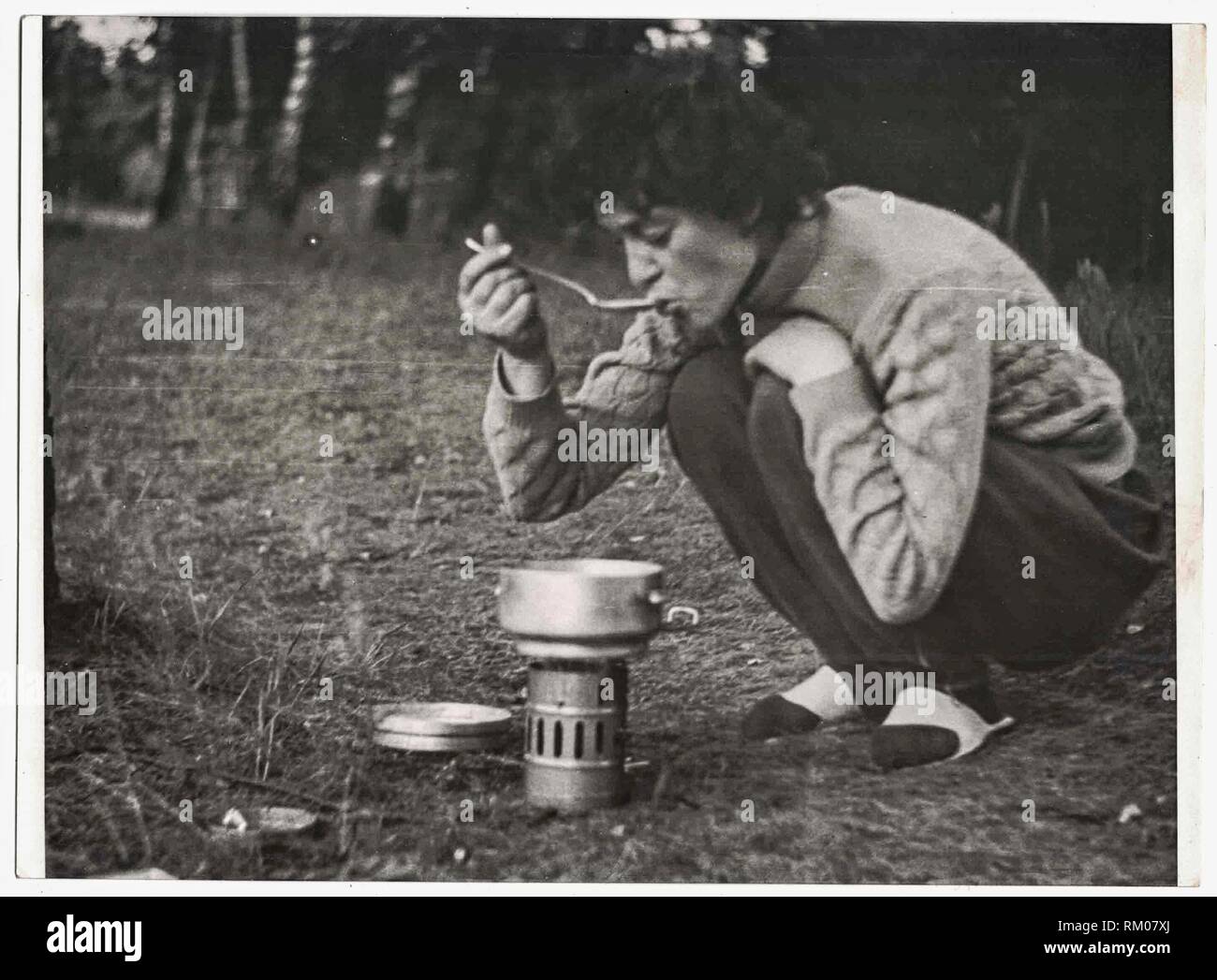 DIE TSCHECHOSLOWAKISCHE SOZIALISTISCHE REPUBLIK - UM 1970s: Retro-Foto zeigt weibliche Touristen, die Essen probieren. Weibliche Touristen kochen Lebensmittel in Camping Topf. Schwarzweißfoto. 1970s Stockfoto
