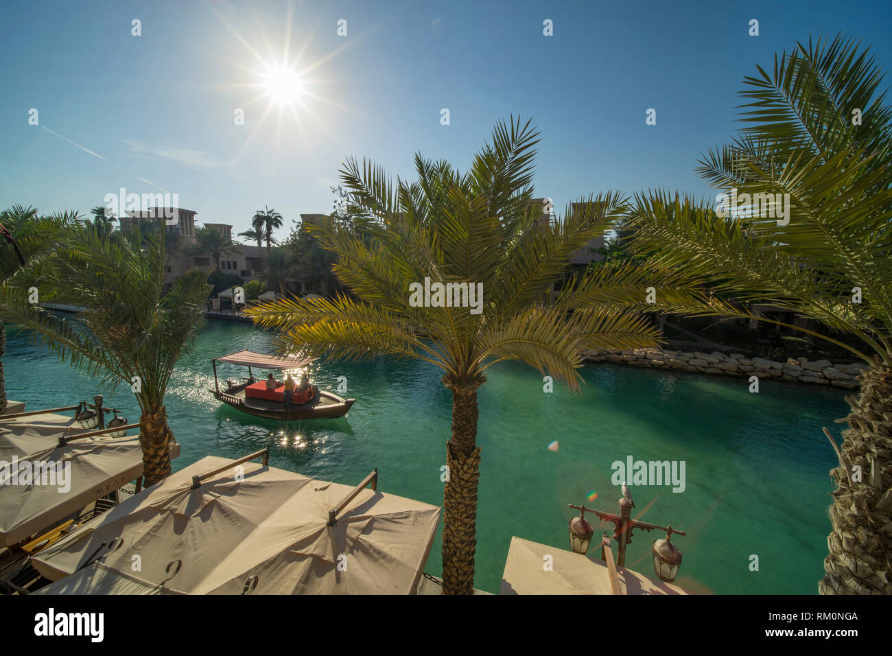 Überdachten arabischen Dhow macht seinen Weg nach unten den blauen Wassern des Souk Madinat Jumeirah und bietet Schatten aus dem mächtigen Desert Sun in dieser grünen Oase. Stockfoto