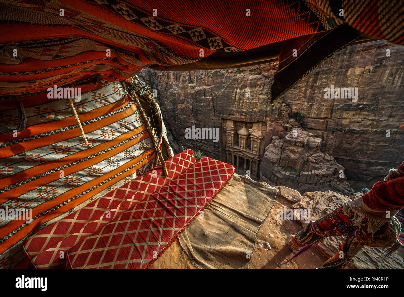Die bunte Decken und Kissen eines cliffside Beduinenzelt Frame die Fassade des berühmten Schatzkammer der Al Khazneh. Stockfoto