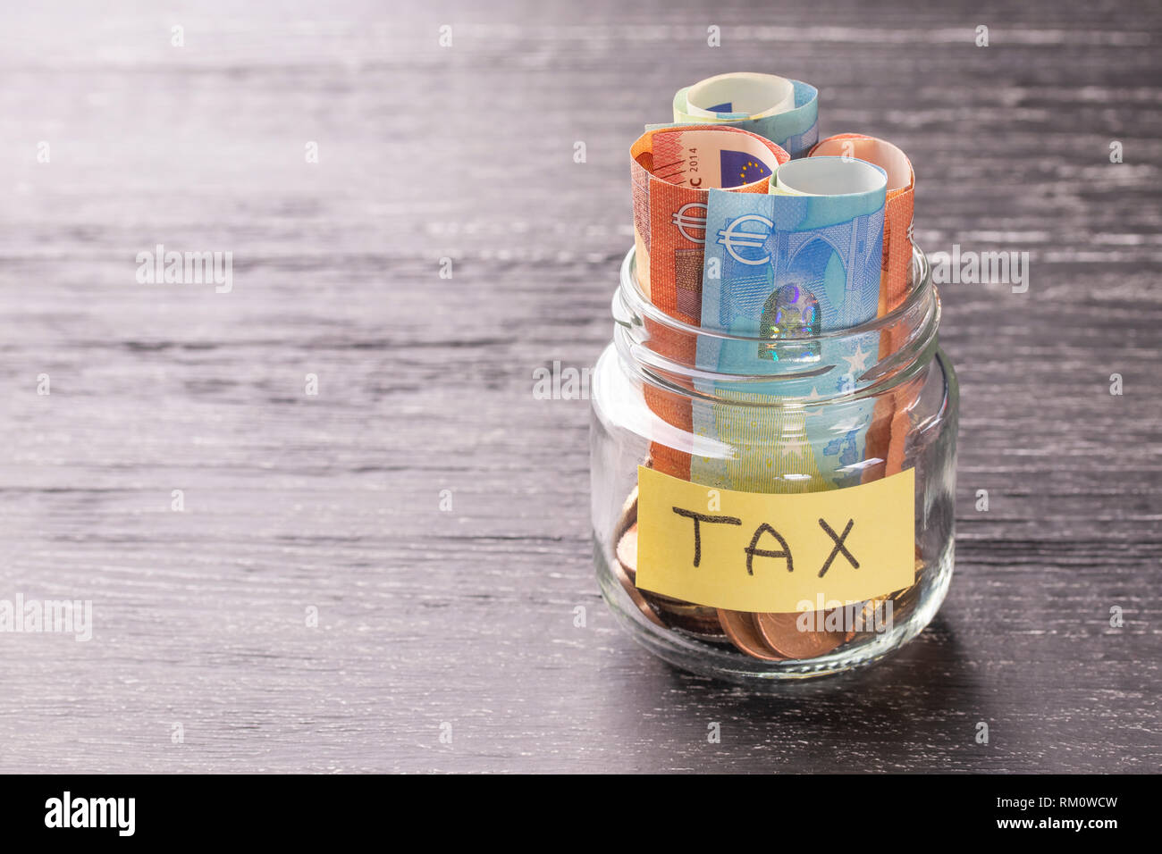 Glas Glas auf einem schwarzen Holztisch mit Münzen und Banknoten und den Worten steuern. Der Begriff des Rechts. Gericht und Entscheidung. Grundsteuer, Haus. Failur Stockfoto