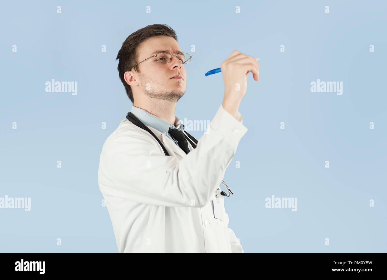 Junge männliche Arzt, medizinische Mitarbeiter, zeigt auf leeren Raum auf auf blauem Hintergrund isoliert. Konzept hält etwas in leere Hand Stockfoto