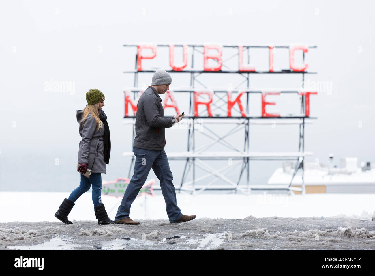 Seattle, Washington: Ein junges paar Kreuze Pine Street am Pike Place Market als starker Wintersturm decken Seattle in sechs Zentimeter Schnee. Stockfoto