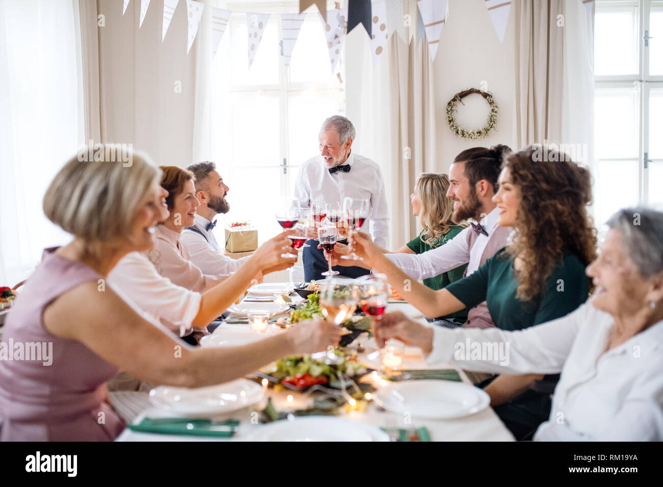 Eine große Familie an einem Tisch sitzen auf einem Indoor Party, anstoßen. Stockfoto