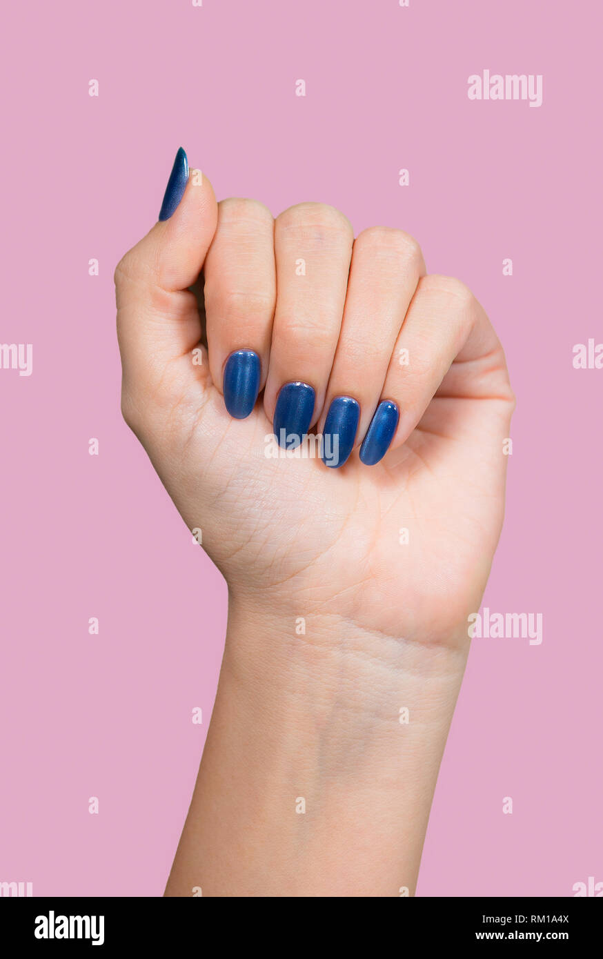 Detailansicht des schönen Eine weibliche Hand mit Blau glänzend professionelle Maniküre auf rosa Hintergrund isoliert. Vertikale Farbfotografie. Stockfoto