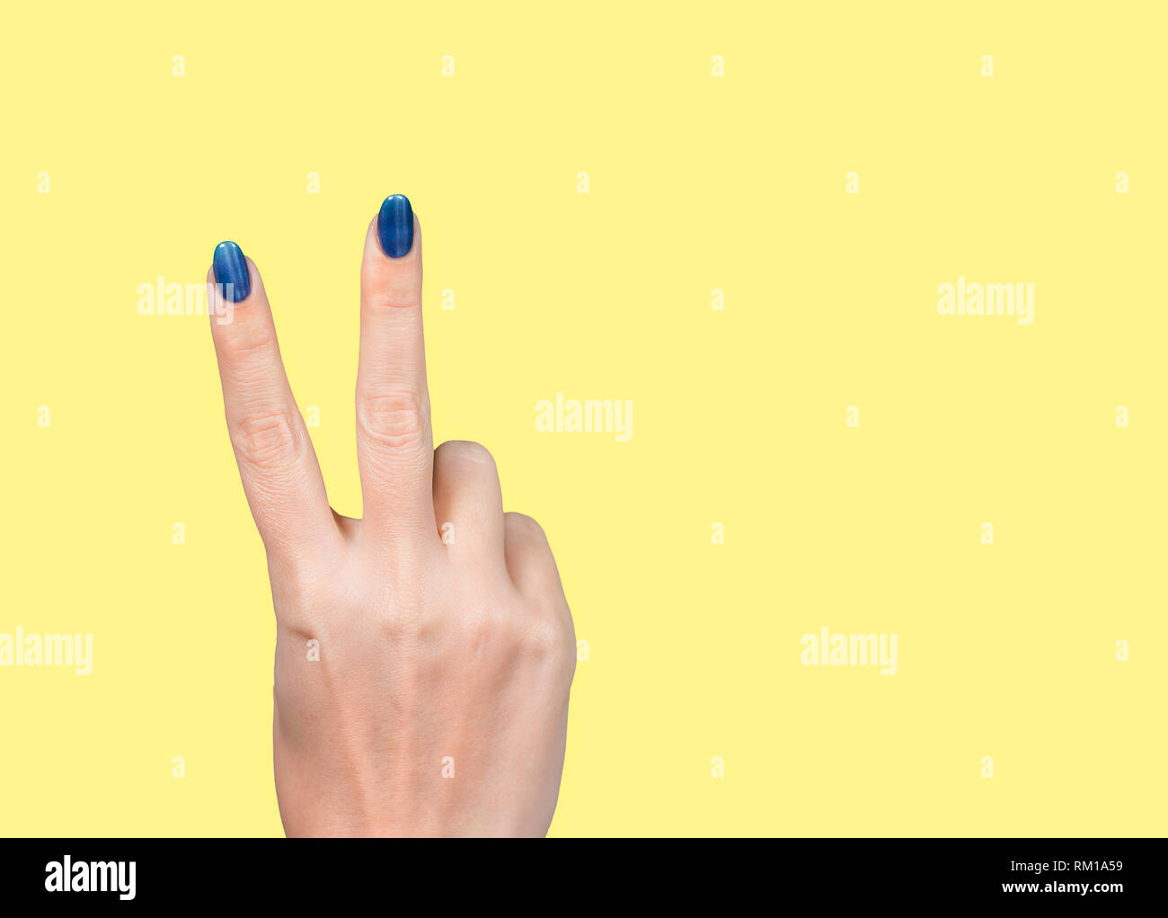 Frau die Hand mit zwei Fingern, die v-Zeichen. Weibliche hand auf gelben Hintergrund. Horizontale Farbfotografie. Stockfoto