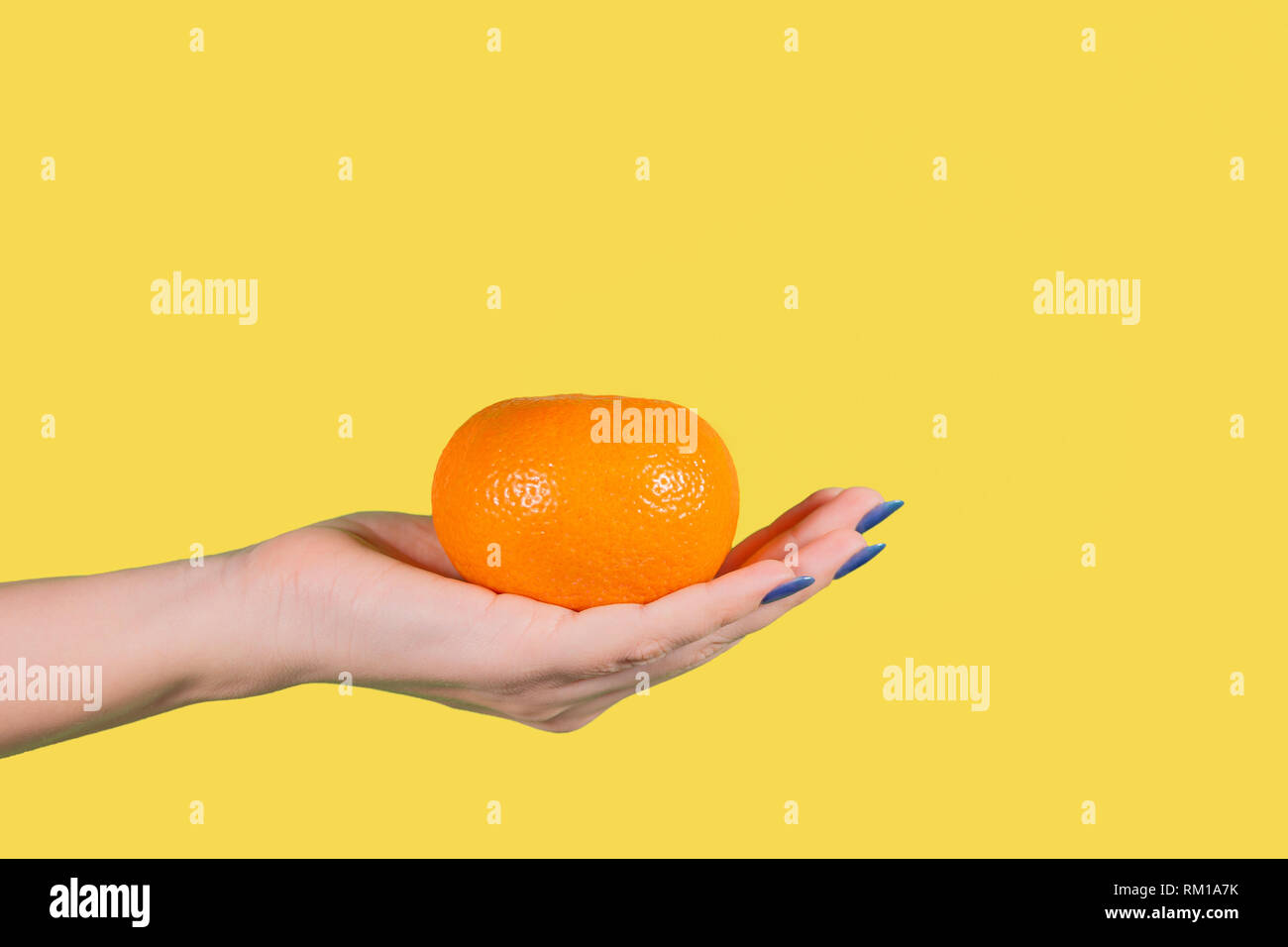 Detailansicht schöne weibliche Hand, die grosse Orange reif Mandarin auf gelbem Hintergrund. Gesunde Ernährung Konzept. Horizontale Farbe Hg Stockfoto