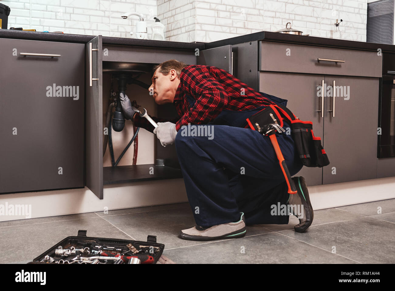 Montage Reparatur mit einem Schraubenschlüssel. Seniour Heimwerker Instandsetzung Waschbecken in der Küche Stockfoto