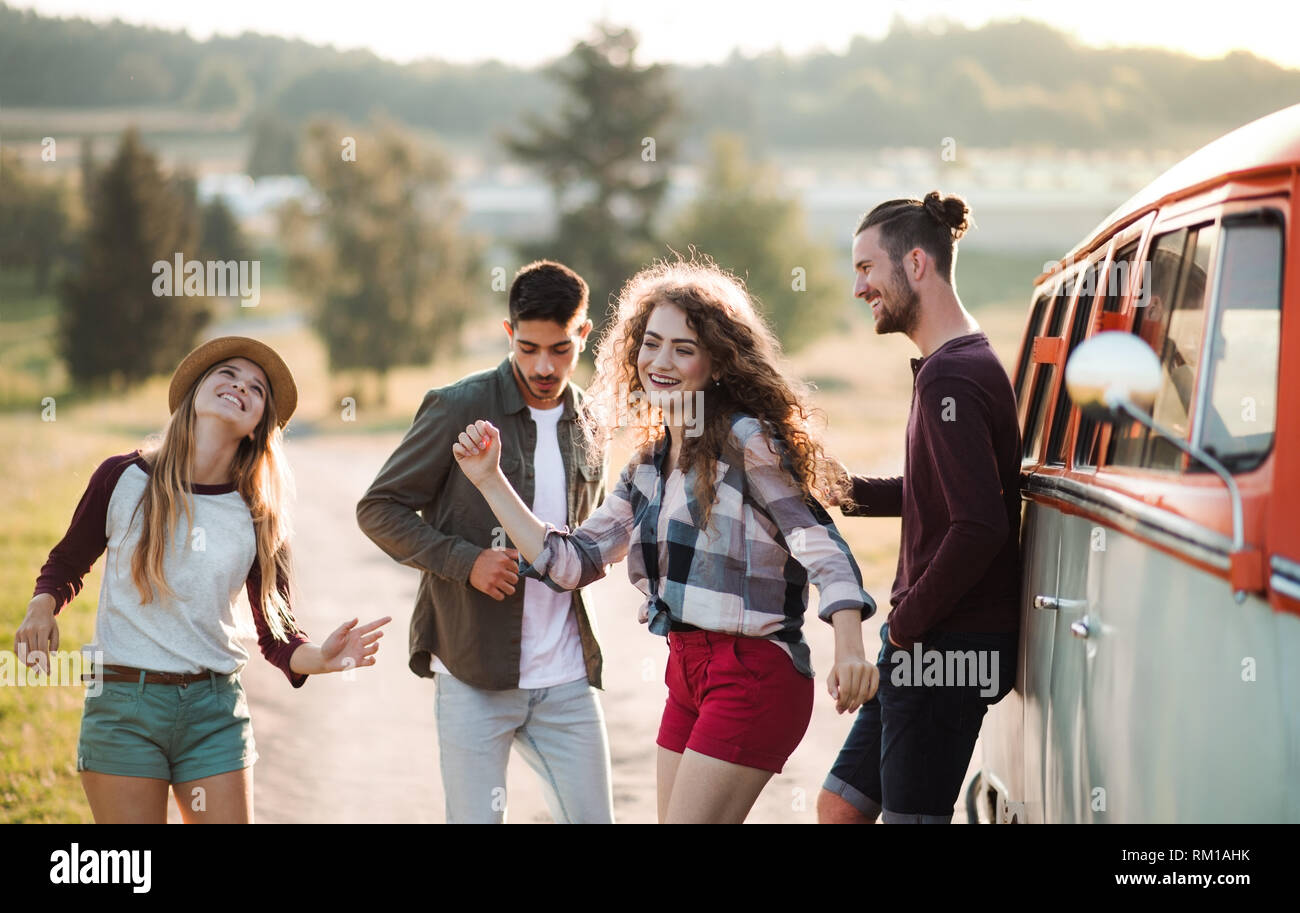 Eine Gruppe junger Freunde auf einem Roadtrip durch Landschaft, tanzen. Stockfoto