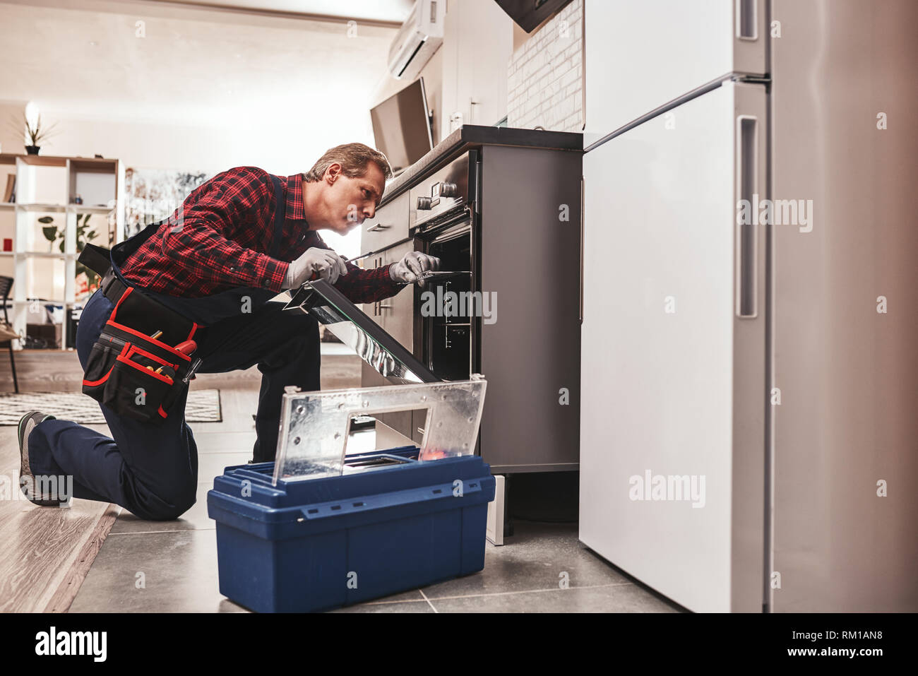 Was oben mit Backofen. Die ganze Länge der reparateur Backofen Prüfung mit Taschenlampe in der Küche im Koffer Stockfoto