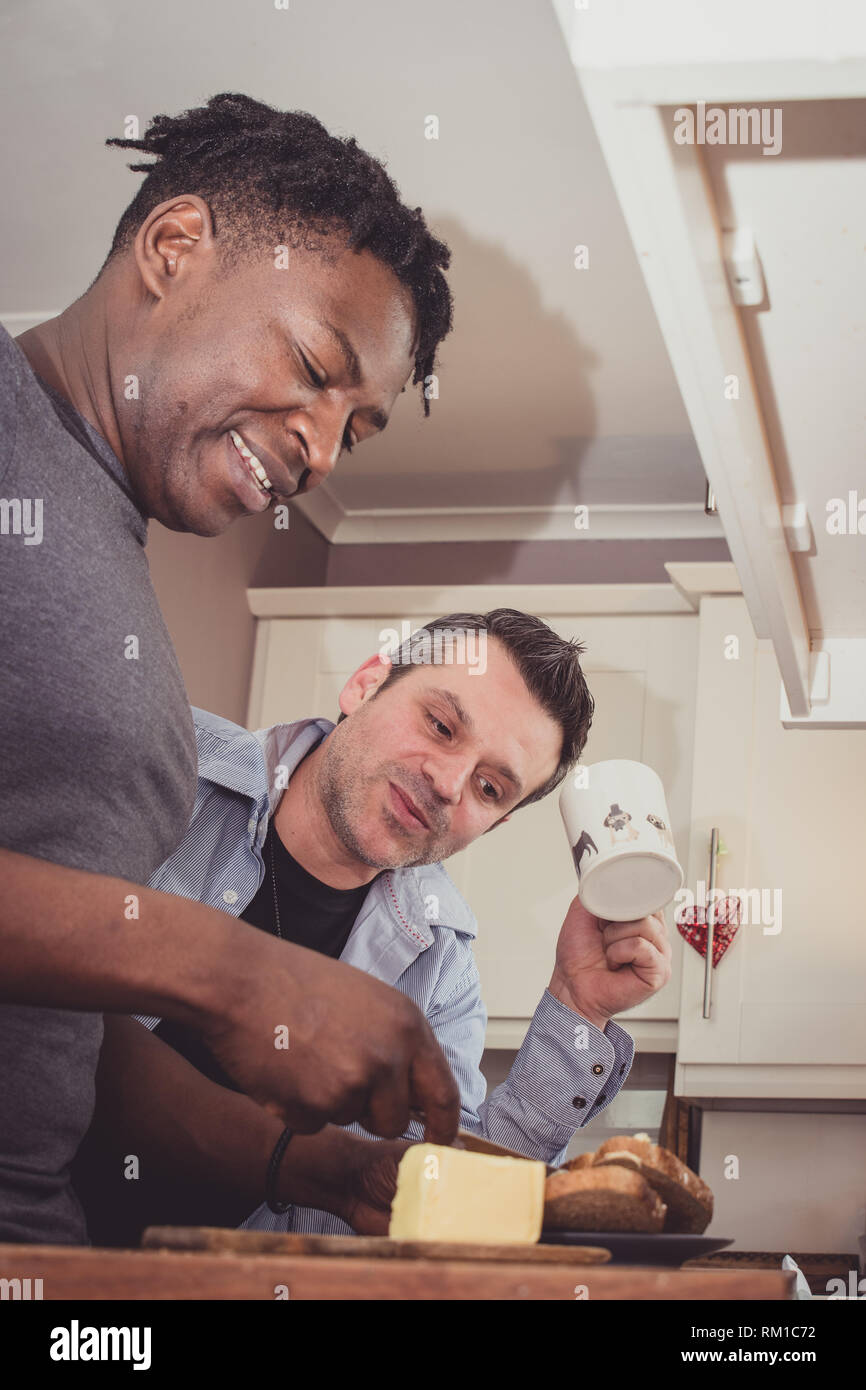 Ein homosexuelles Paar Geschichten von Ihren Tag bei der Arbeit über eine Scheibe Toast und eine Tasse Tee und Kaffee am Abend. Stockfoto