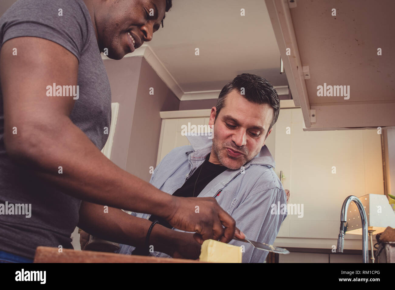 Ein homosexuelles Paar Geschichten von Ihren Tag bei der Arbeit über eine Scheibe Toast und eine Tasse Tee und Kaffee am Abend. Stockfoto