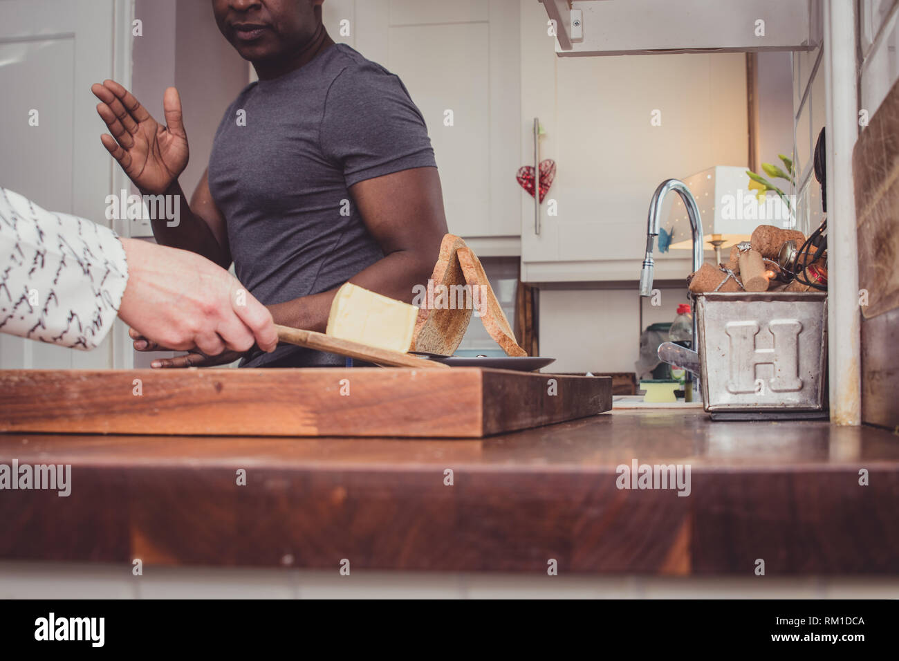 Ein homosexuelles Paar Geschichten von Ihren Tag bei der Arbeit über eine Scheibe Toast und eine Tasse Tee und Kaffee am Abend. Stockfoto