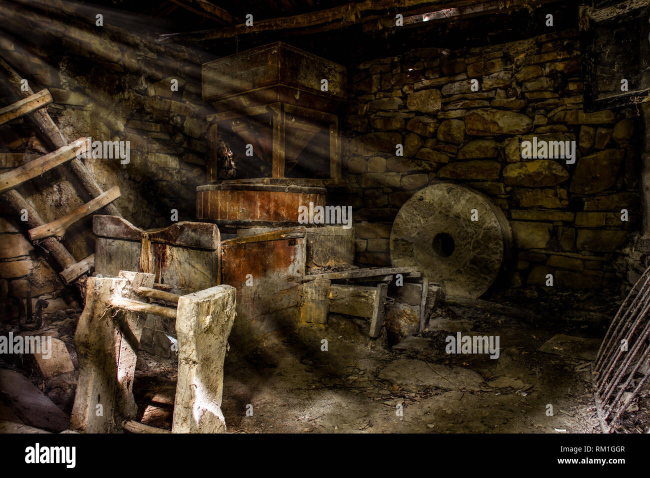 Sonnenstrahlen, die durch die Sprünge auf dem Dach, und leuchtet Innenräume der alten Wassermühle, großen runden Stein, Leitern usw., lange nicht mehr benutzen. Stockfoto