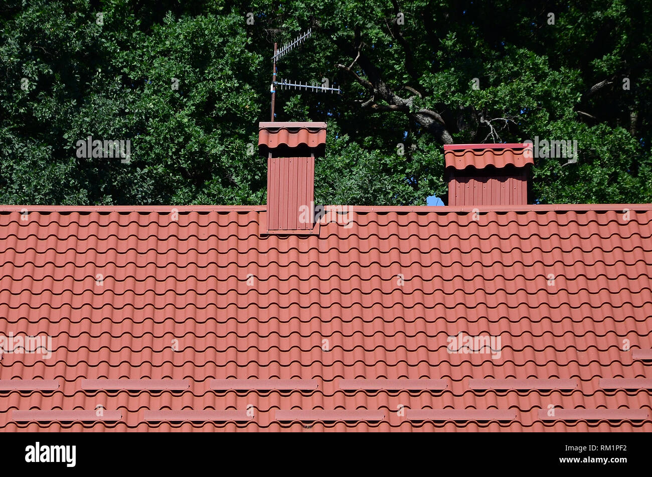 Hochwertige rote Metall Fliesen Dach eines Hauses gegen grüne Bäume Hintergrund Stockfoto